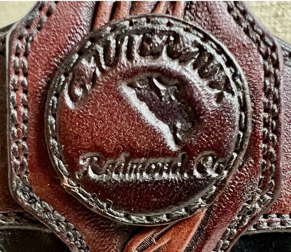 Round stamped leather badge reading Gauteraux above a bucking bronc and rider, with Redmond OR in script below, stitched onto a tooled oxblood boot